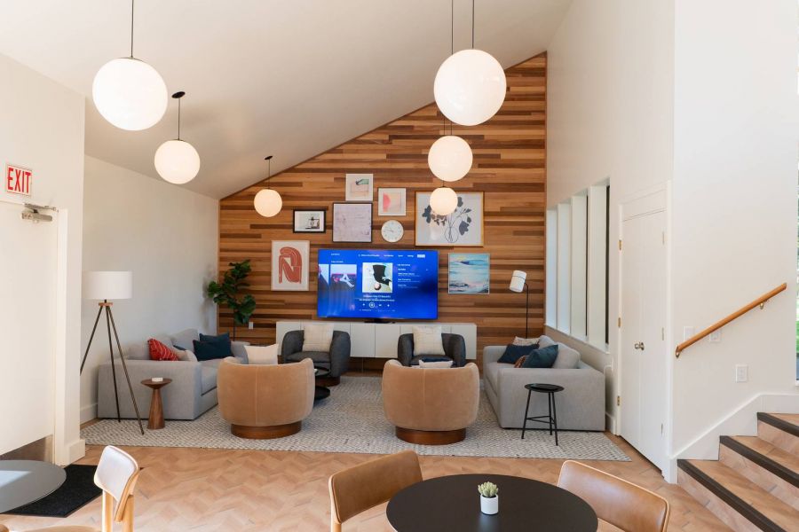 Northgreen Apartments Modern lounge with wooden accents, round tables, chairs, sofas, wall art, and hanging globe lights.