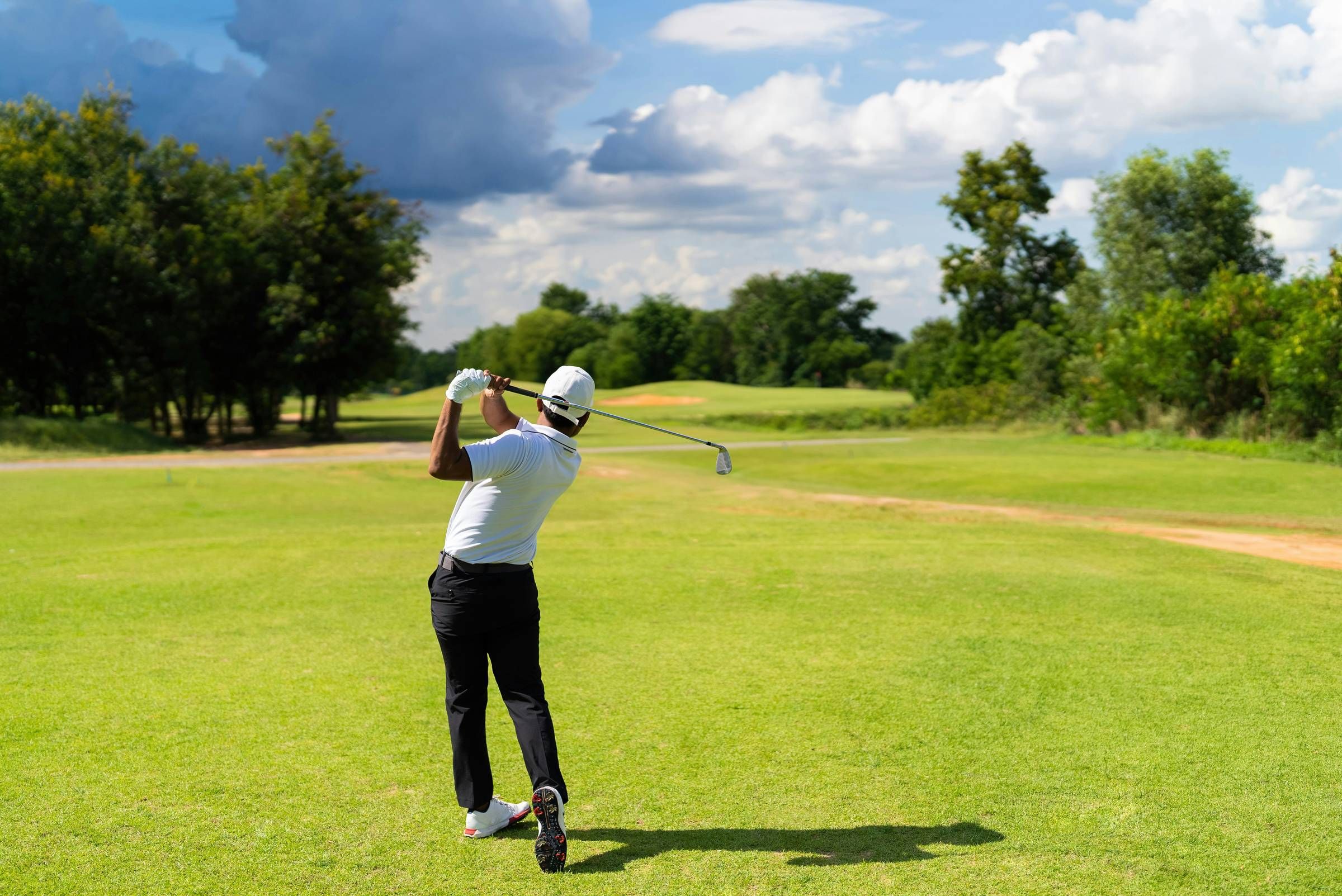Northgreen Apartments A golfer in a white shirt swings a club on a green course under a partly cloudy sky.