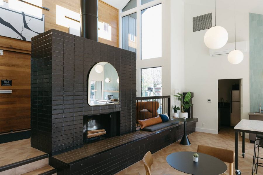 Northgreen Apartments Modern living space with black brick fireplace, wood floors, round dining table, and large windows.