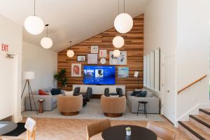 Northgreen Apartments Modern lounge with wooden accents, round tables, chairs, sofas, wall art, and hanging globe lights.