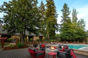 Northgreen Apartments Modern outdoor lounge with red and gray seating, a fire pit, and a swimming pool surrounded by tall trees.