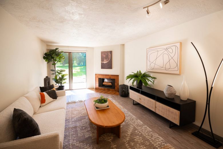 Northgreen Apartments Bright, modern living room with neutral decor, houseplants, a sofa, coffee table, and large window.