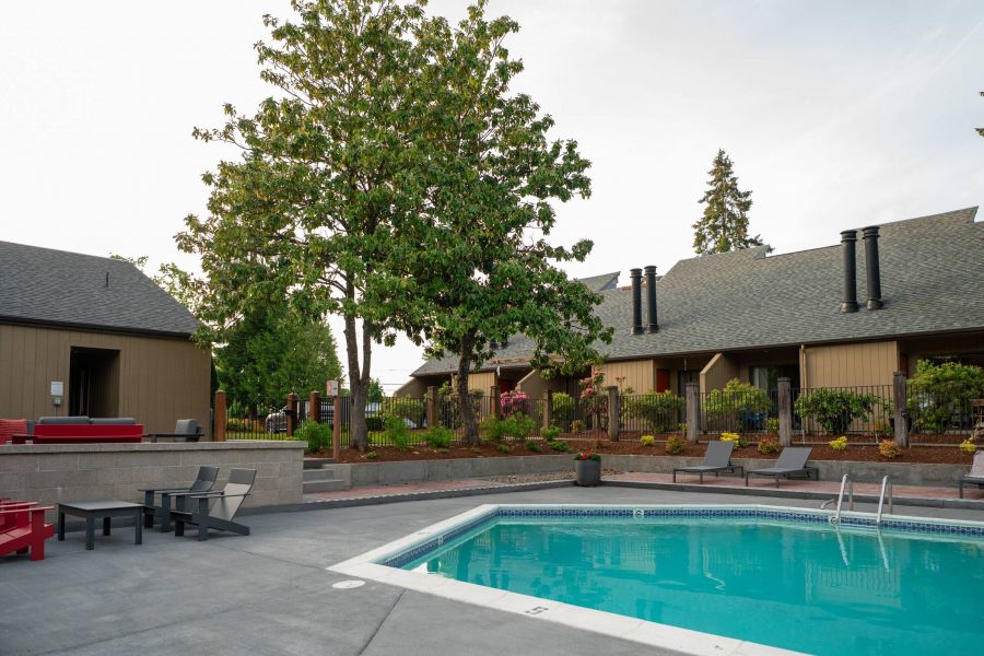 Northgreen Apartments Outdoor swimming pool with patio seating, surrounded by trees and apartment buildings in the background.